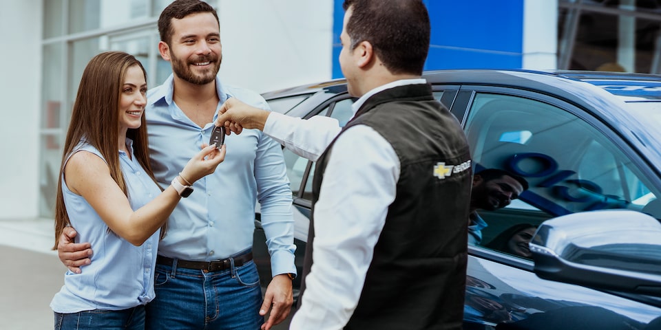 Pareja recibiendo las llaves de su Chevrolet Seminuevo con garantía y certificado